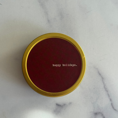 Red lid with 'happy holidays.' text on a marble surface