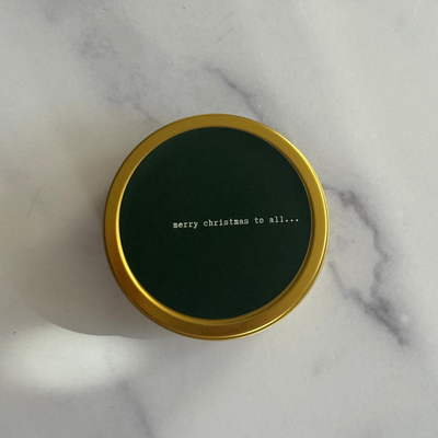 Gold tin candle with green label on a marble surface